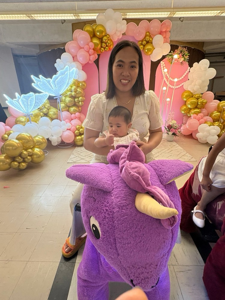 Child riding a purple pony at a party