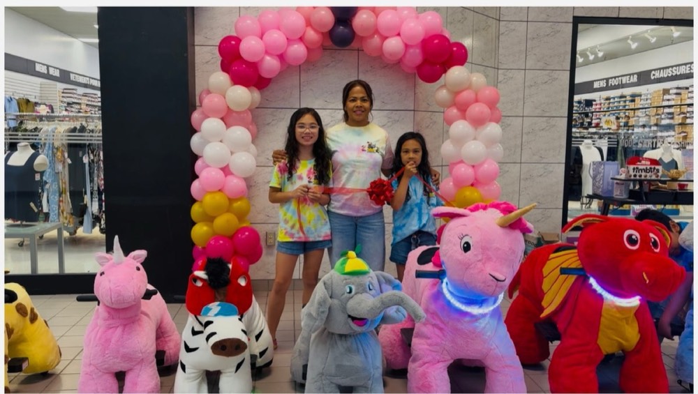 Ride-ons at a birthday party with a balloon arch